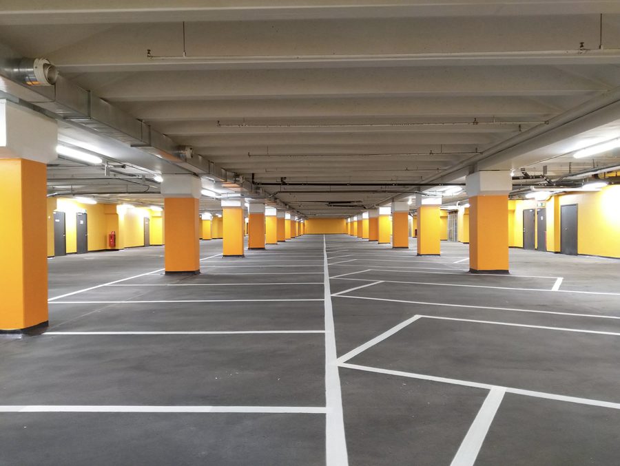 Ljust garage med gula pelare och markerade parkeringsplatser.